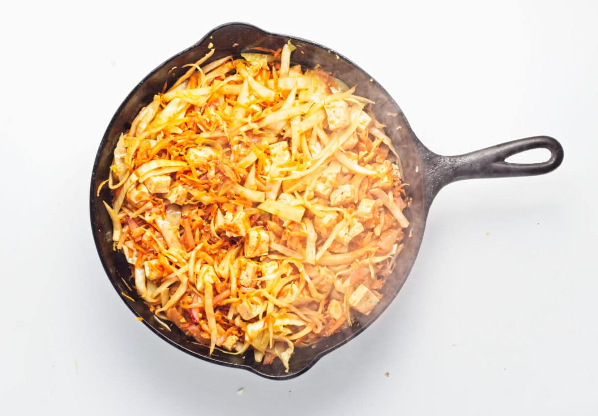 adding sauce to cabbage, carrot, and radish.