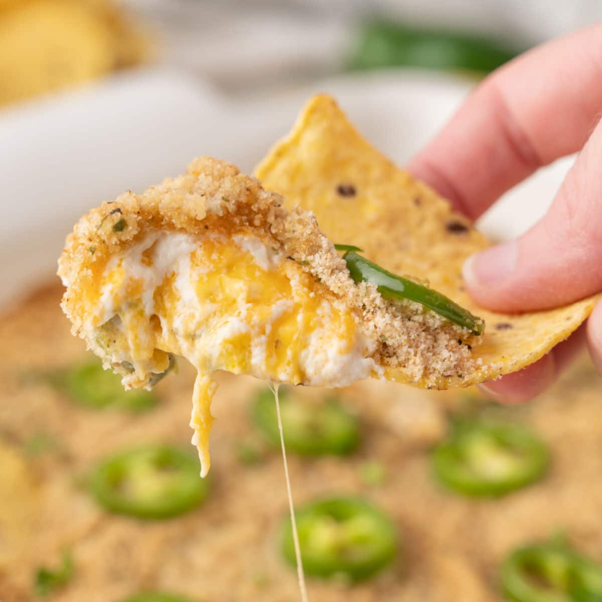 dipping tortilla chip in jalapeno popper