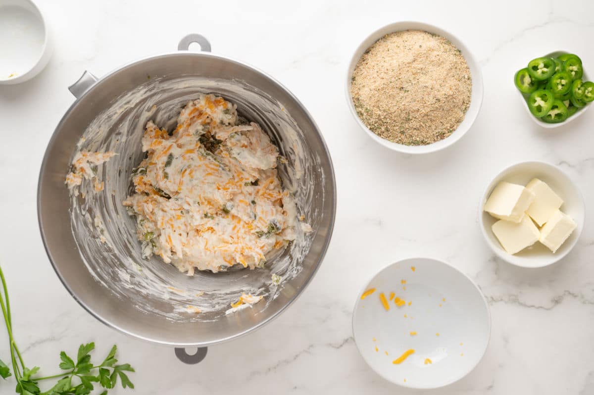 adding jalapenos to the cream cheese mixture with the shredded cheddar cheese