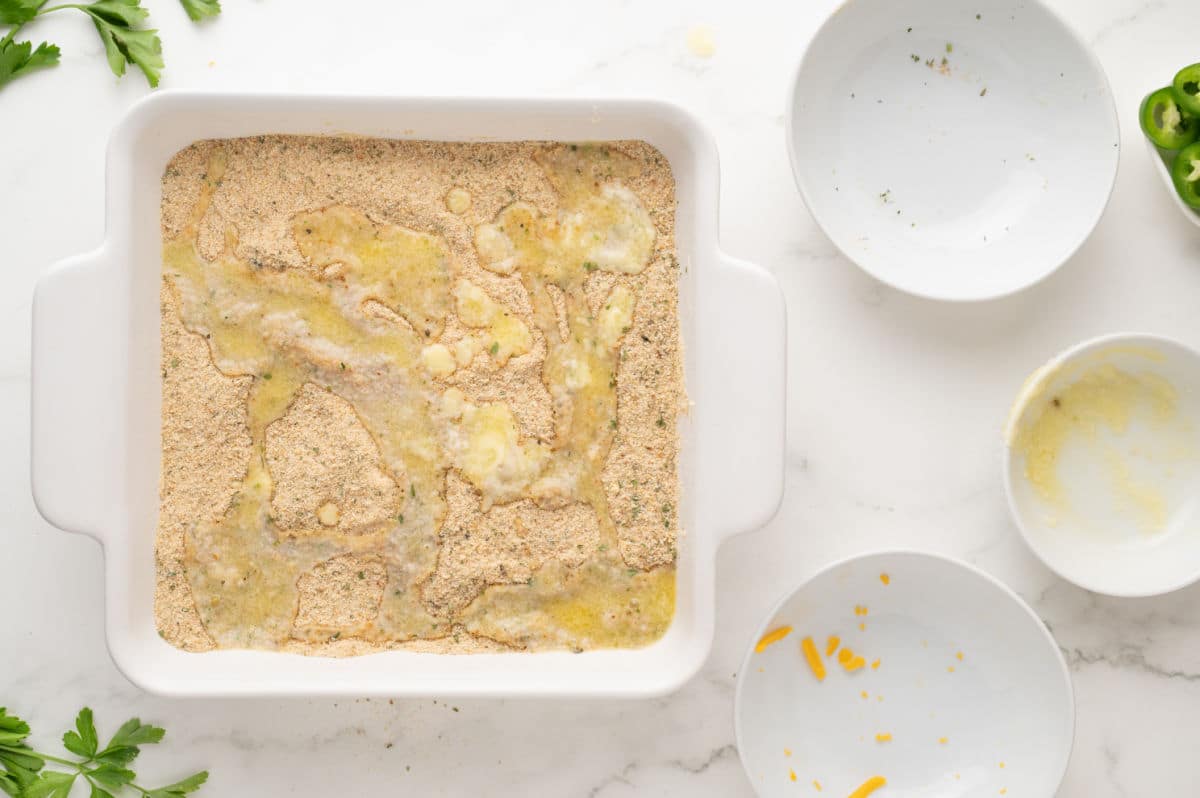 putting bread crumbs on top of mixture, then adding melted butter.