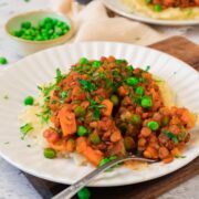 A plate of hearty lentil stew over mashed potatoes on a white plate
