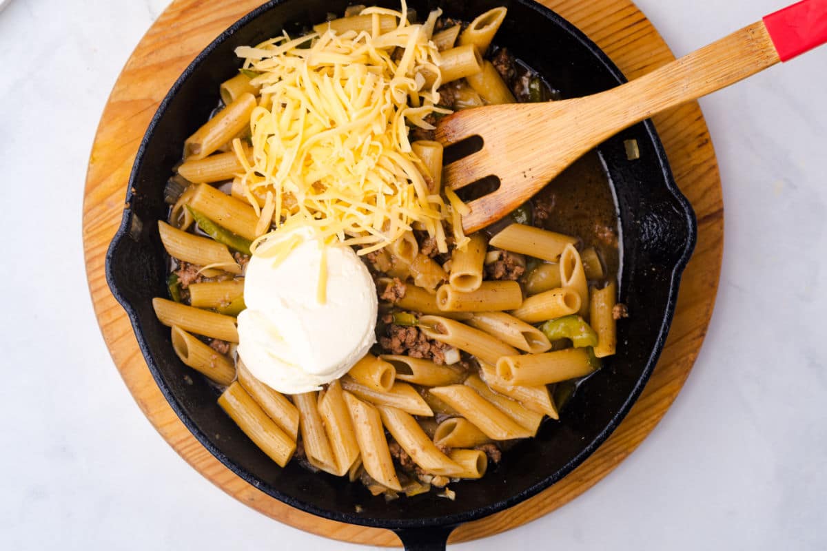 adding cubed cream cheese and half of the Provolone cheese to the skillet
