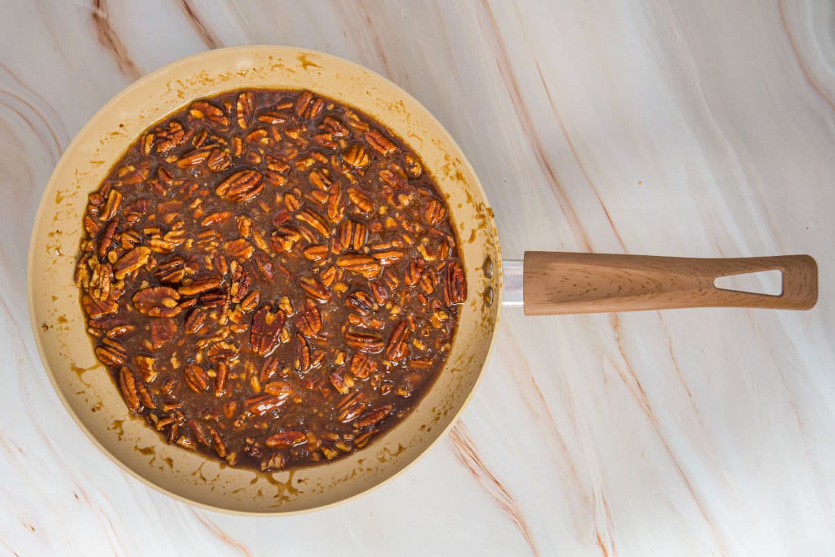 Adding chopped pecans, heavy cream, salt, and vanilla extract.