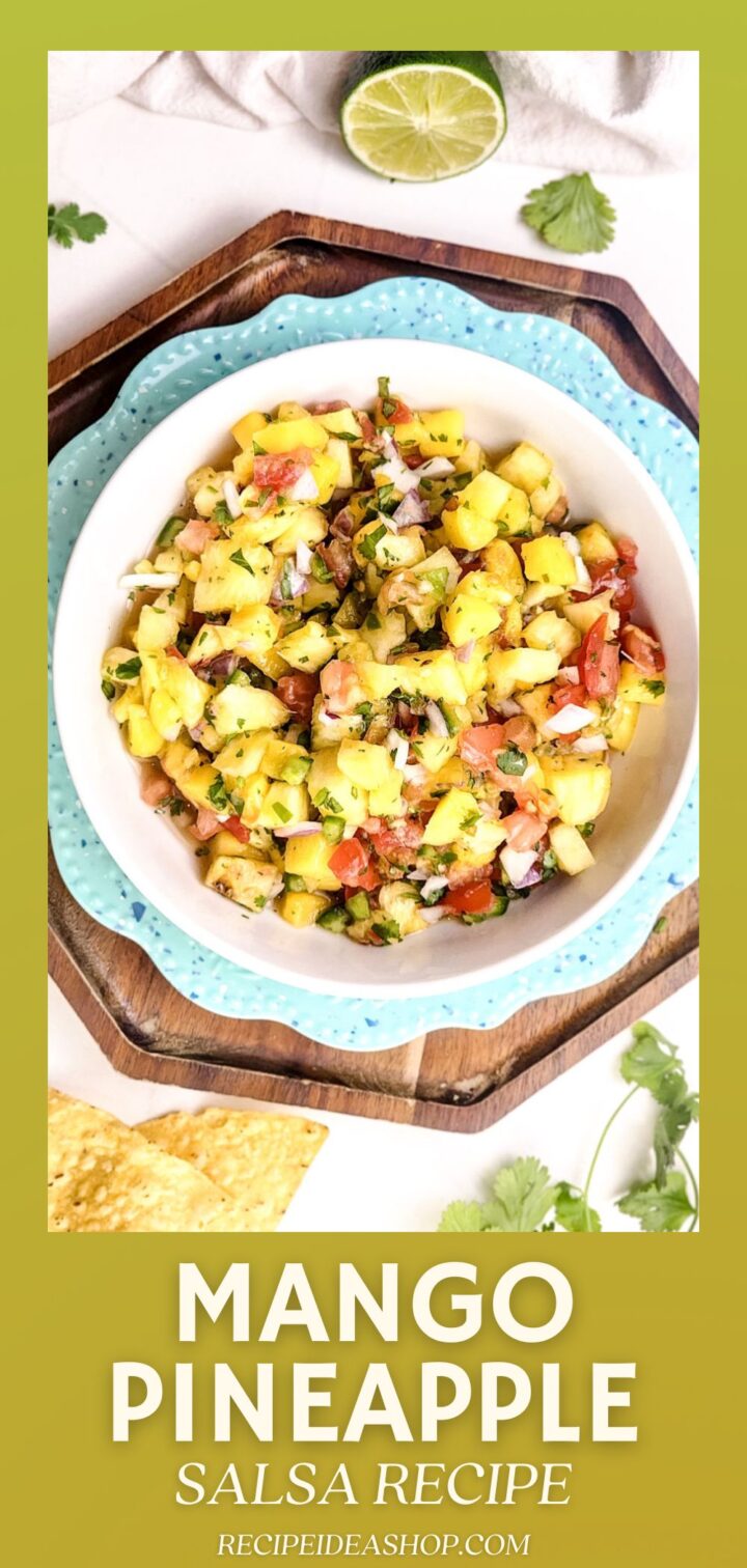 A bowl of colorful Mango Pineapple Salsa with tomatoes, onions, and cilantro sits on a blue-rimmed plate. Lime, cilantro, and tortilla chips are nearby. Text at the bottom reads Mango Pineapple Salsa Recipe.