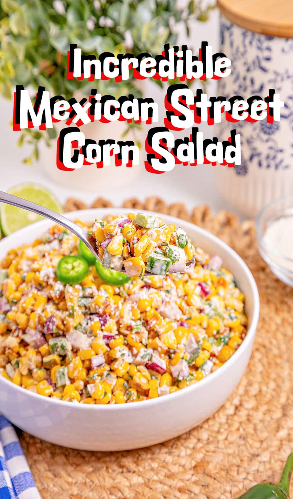 A bowl of colorful Mexican Street Corn salad with chopped vegetables, topped with cheese and jalapeño slices. A spoon lifts a portion, and bold text reads Incredible Mexican Street Corn Salad.