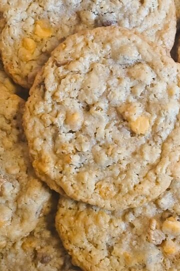A close-up of several kitchen sink cookies piled together, with visible oats and butterscotch chips overlapping each other in a delicious heap.