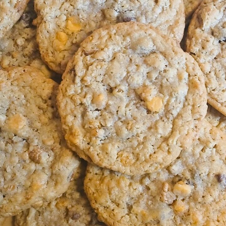 A close-up of several kitchen sink cookies piled together, with visible oats and butterscotch chips overlapping each other in a delicious heap.