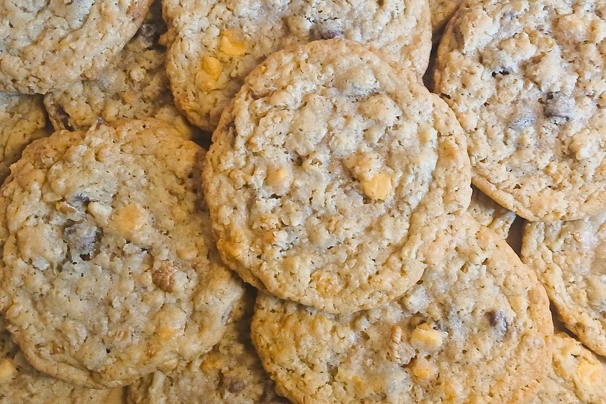 A close-up of several kitchen sink cookies piled together, with visible oats and butterscotch chips overlapping each other in a delicious heap.