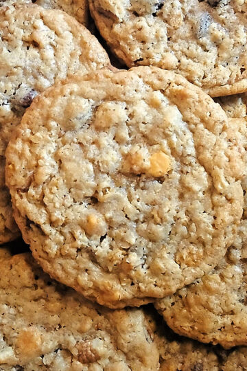 A close-up of several homemade oatmeal ice cream scoop cookies with visible oats and chocolate or butterscotch chips stacked together.