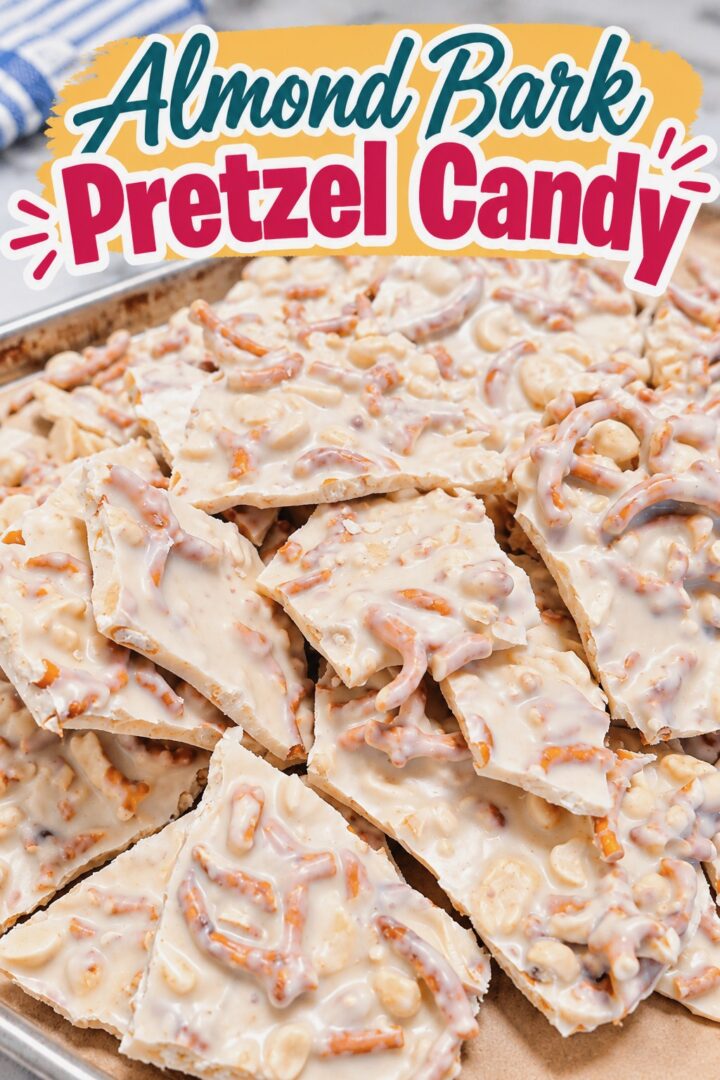 Pieces of almond bark pretzel candy rest on a parchment-lined baking sheet.