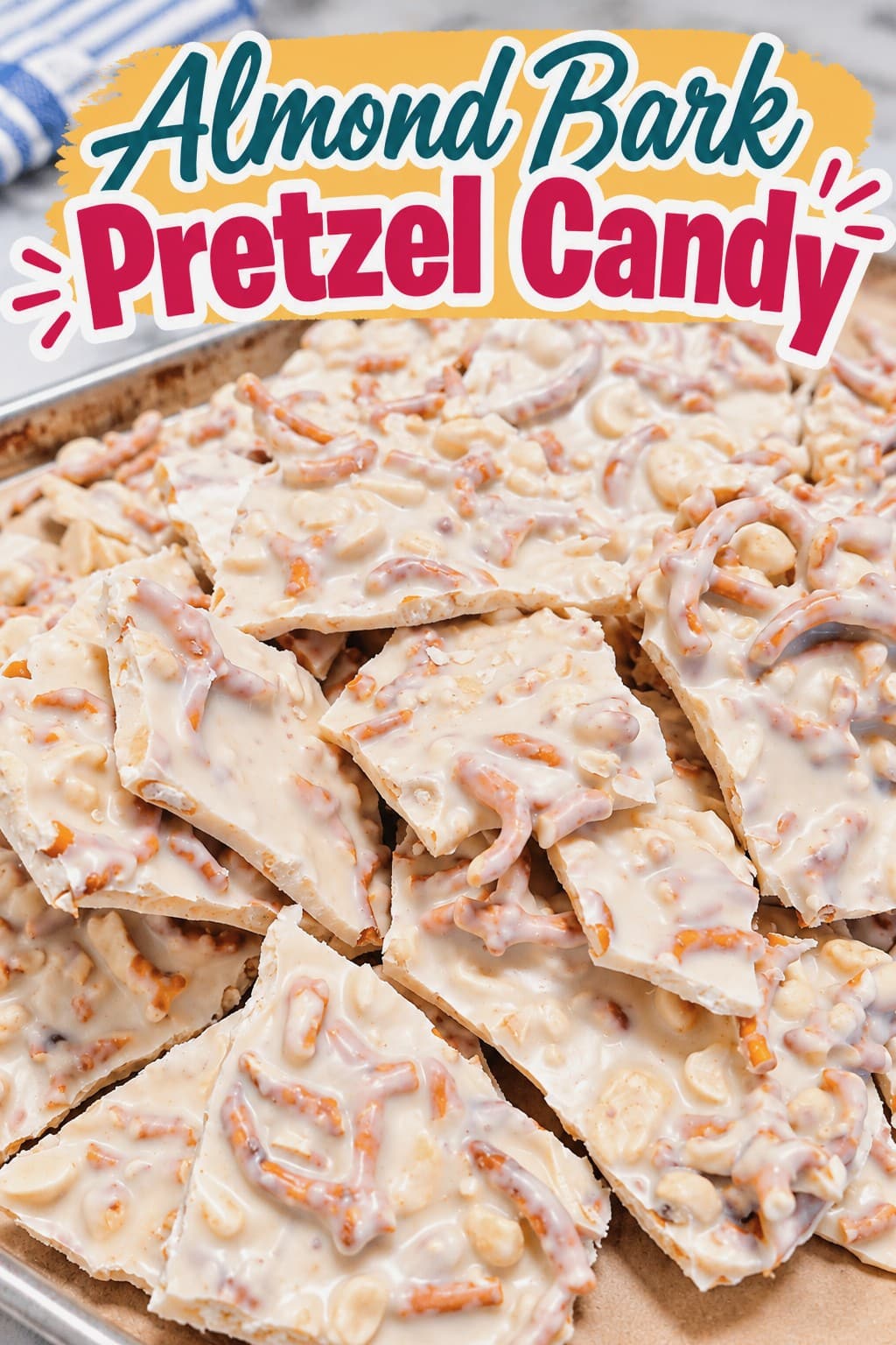 Pieces of almond bark pretzel candy rest on a parchment-lined baking sheet.
