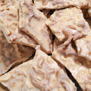 Pieces of white almond bark filled with peanuts and pretzel bits.