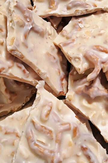 Pieces of white almond bark filled with peanuts and pretzel bits.