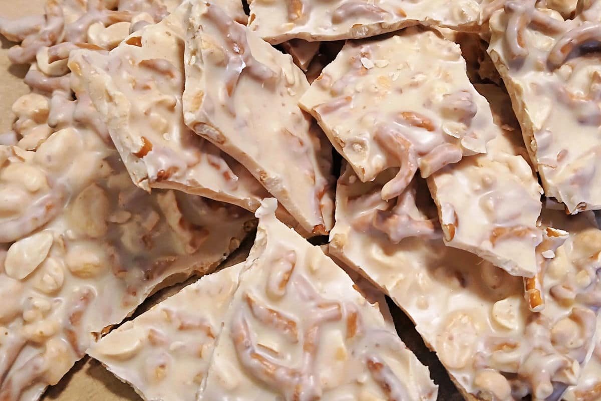 Pieces of white almond bark filled with peanuts and pretzel bits.