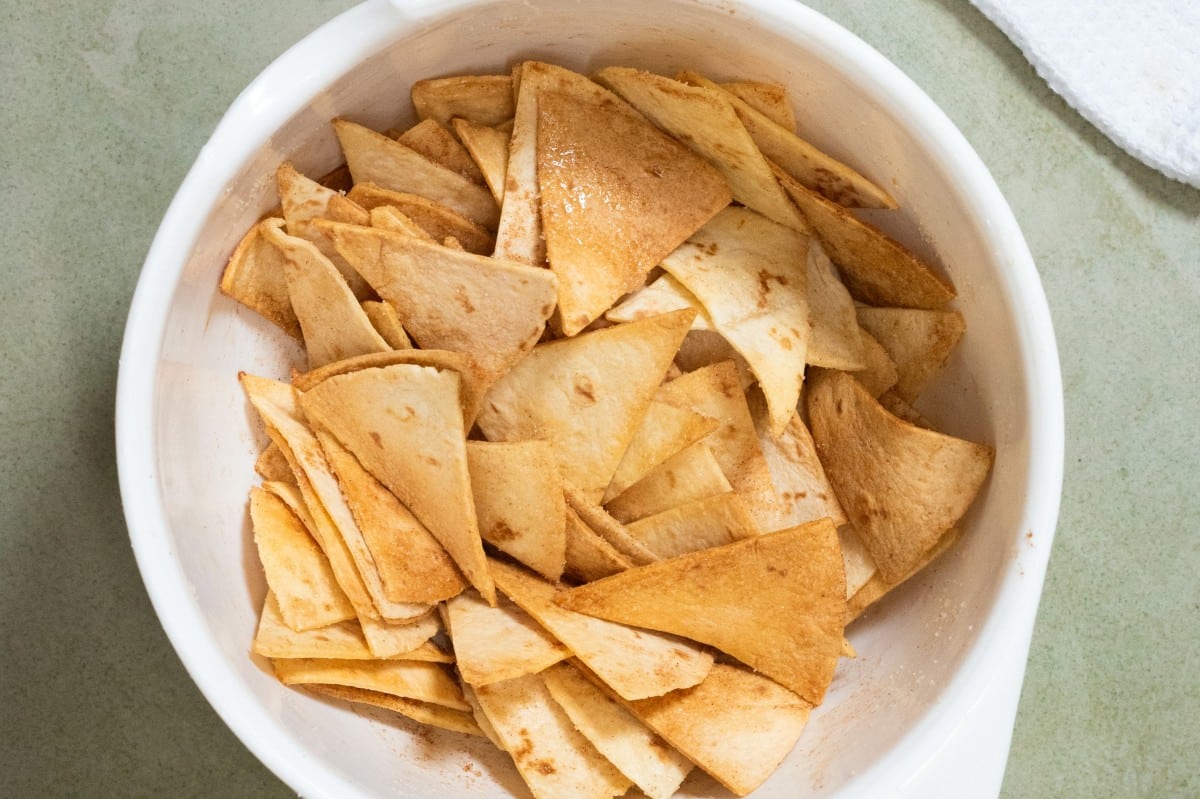 A white bowl filled with triangle-shaped cinnamon sugar pita chips for fresh fruit salsa.